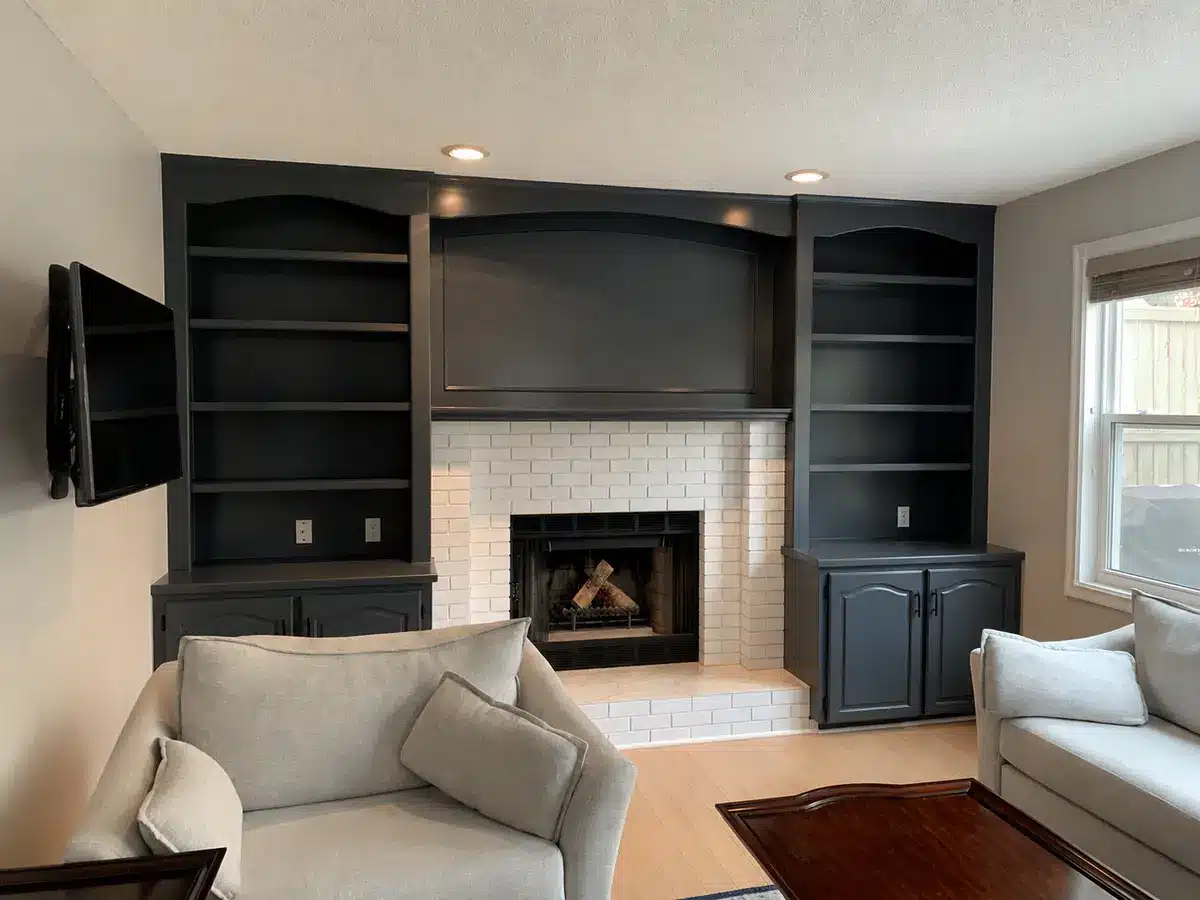 Living room built-ins painted charcoal beside a white brick fireplace